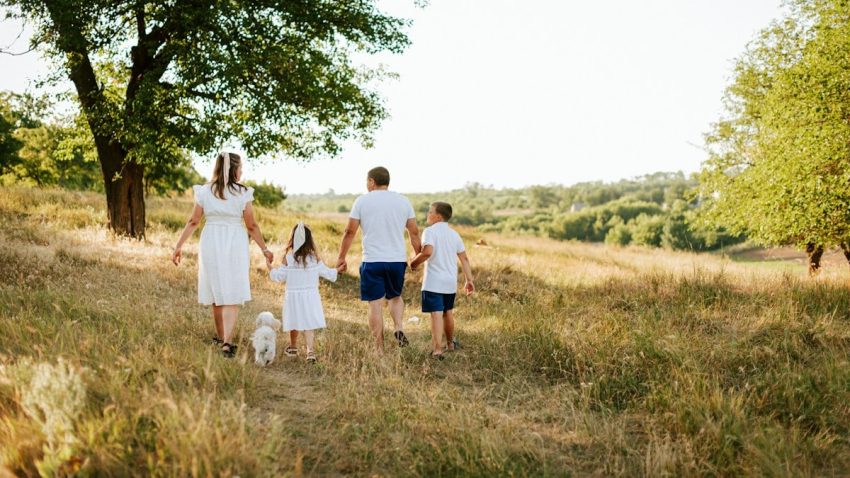 A family walking through a field with a dog